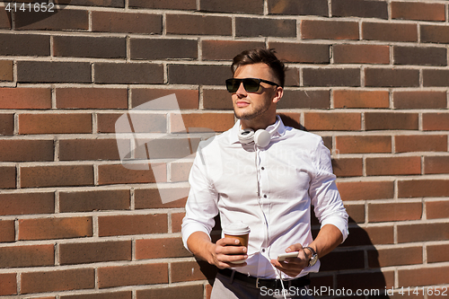 Image of man with smartphone and coffee cup on city street