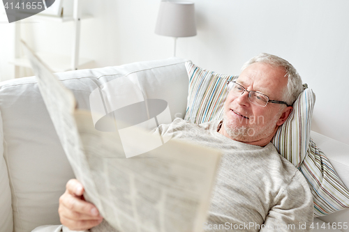 Image of close up of senior man reading newspaper at home