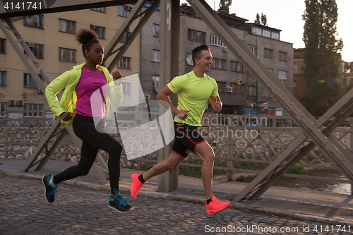Image of young multiethnic couple jogging in the city