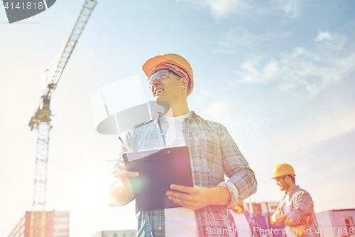 Image of builder in hardhat with clipboard at construction