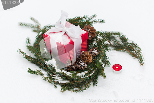 Image of christmas gift and fir wreath with cones on snow