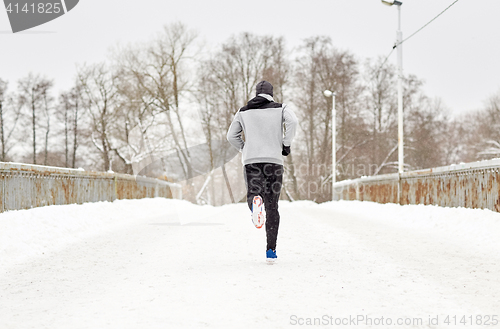 Image of man running along snow covered winter bridge road