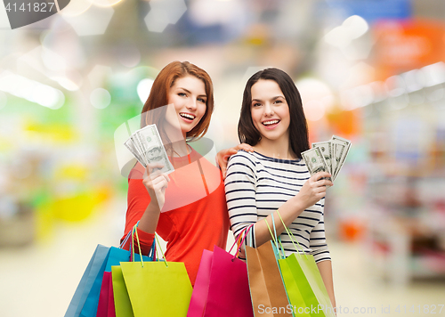 Image of smiling teenage girls with shopping bags and money