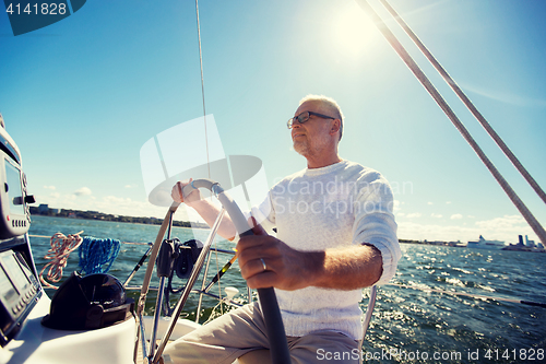 Image of senior man at helm on boat or yacht sailing in sea