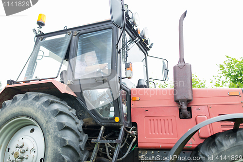 Image of senior man driving tractor at farm