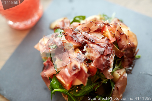 Image of prosciutto ham salad on stone plate at restaurant