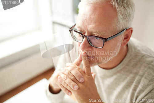 Image of close up of senior man in glasses thinking