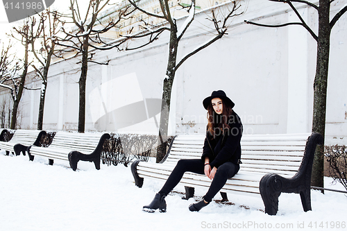 Image of young pretty modern hipster girl waiting on bench at winter snow park alone, lifestyle people concept