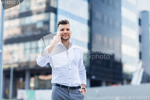 Image of happy man with smartphone calling on city street