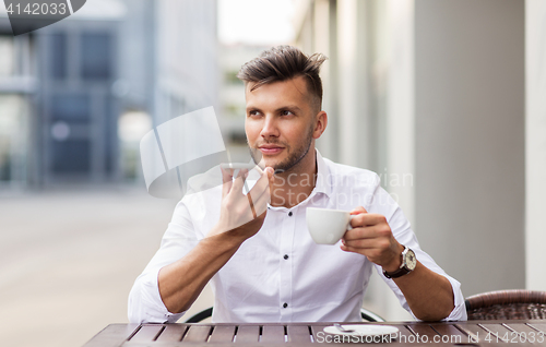 Image of man with coffee and smartphone at city cafe