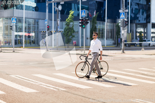 Image of young man with bicycle on crosswalk in city