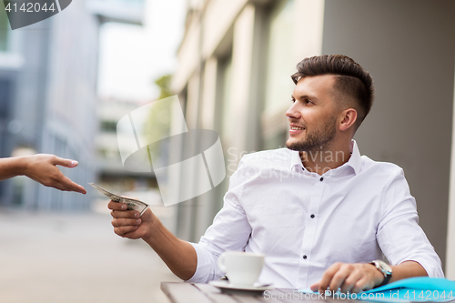 Image of man with dollar money paying for coffee at cafe