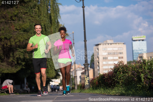 Image of young smiling multiethnic couple jogging in the city