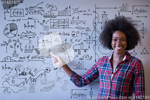 Image of African American woman writing on a chalkboard in a modern offic