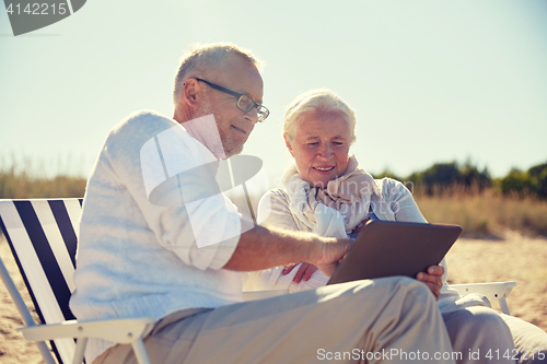 Image of happy senior couple with tablet pc on summer beach