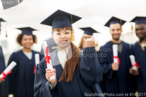 Image of happy students in mortar boards with diplomas