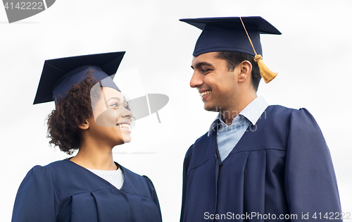 Image of happy students or bachelors in mortar boards