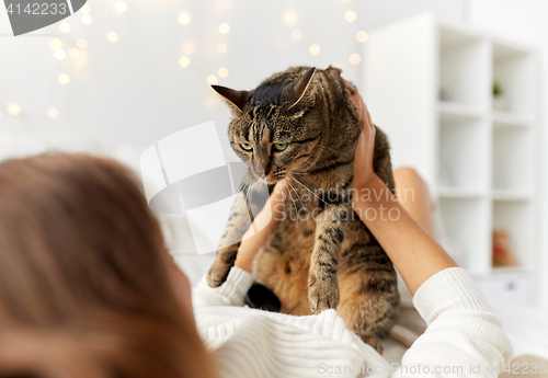 Image of young woman with cat lying in bed at home