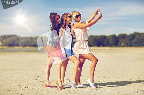 Image of group of smiling women taking selfie on beach