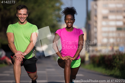 Image of jogging couple warming up and stretching in the city