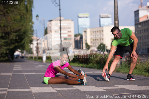 Image of jogging couple warming up and stretching in the city