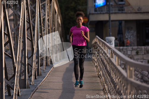 Image of african american woman running across the bridge