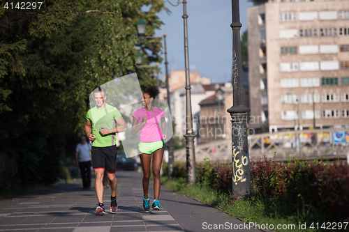 Image of young smiling multiethnic couple jogging in the city