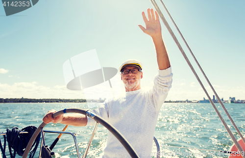 Image of senior man at helm on boat or yacht sailing in sea