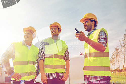 Image of happy male builders in vests with walkie talkie