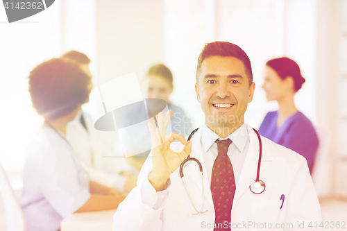 Image of happy doctor over group of medics at hospital