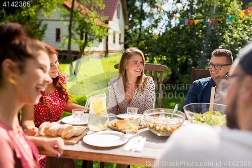 Image of happy friends having dinner at summer garden party