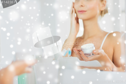 Image of close up of woman applying face cream at bathroom
