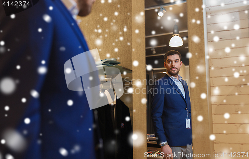 Image of man trying jacket on at mirror in clothing store