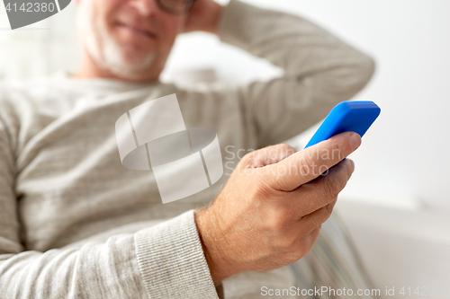 Image of close up of old man texting on smartphone at home