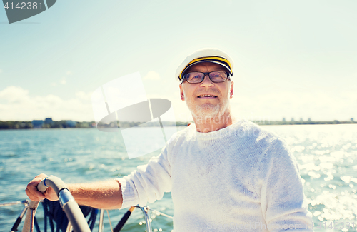 Image of senior man at helm on boat or yacht sailing in sea