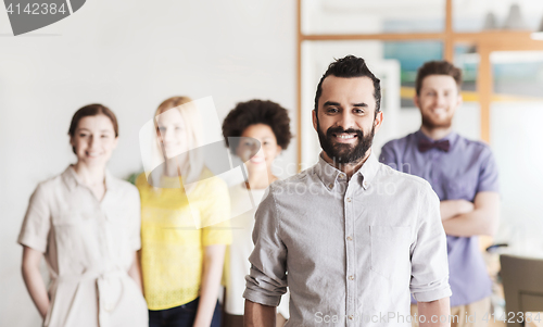 Image of happy young man over creative team in office
