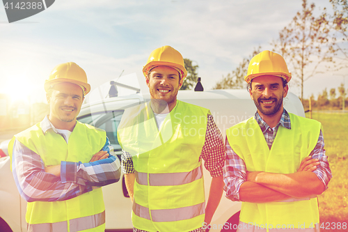 Image of happy male builders in high visible vests outdoors