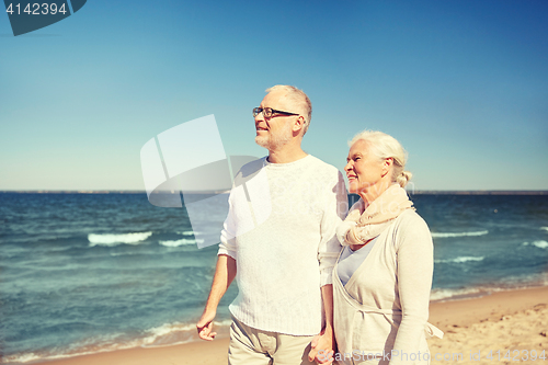 Image of happy senior couple walking along summer beach