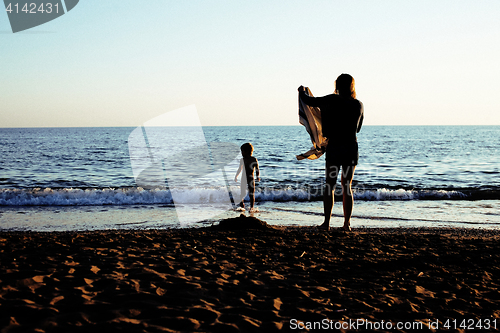 Image of young mother with son resting on sea coast, happy family togethe