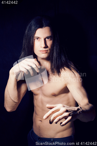 Image of handsome young man with long hair naked torso on black backgroun