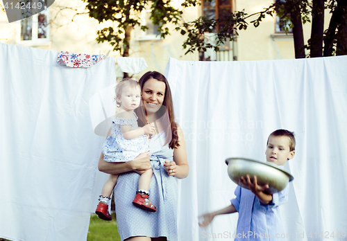Image of woman with children in garden hanging laundry outside, lifestyle