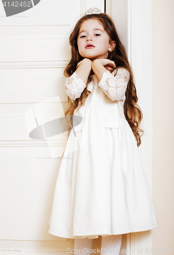 Image of little cute girl at home, opening door well-dressed in white dre