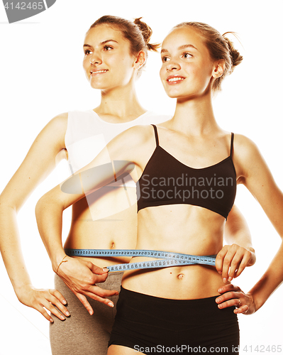 Image of two sport girls measuring themselves isolated on white