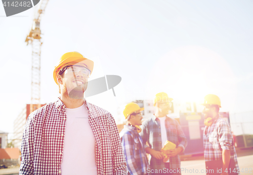 Image of group of smiling builders in hardhats outdoors