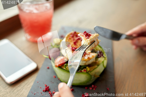 Image of woman eating goat cheese salad at restaurant