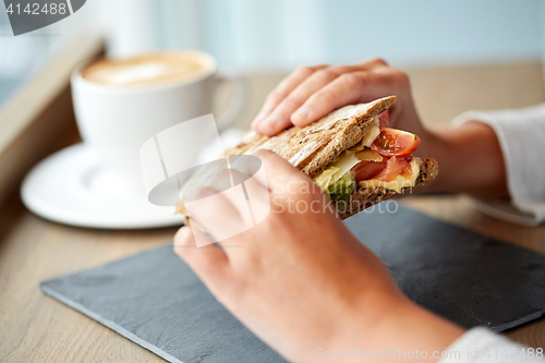 Image of woman eating salmon panini sandwich at restaurant