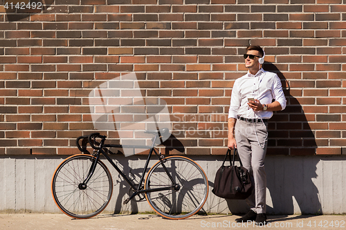 Image of man with headphones, smartphone and bicycle