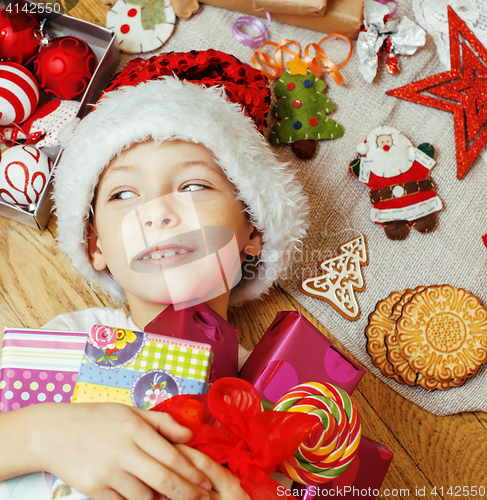 Image of little cute kid in santas red hat with handmade gifts, toys vintage wooden, warm winter