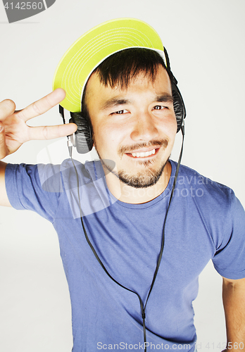 Image of young asian man in hat and headphones listening music on white b