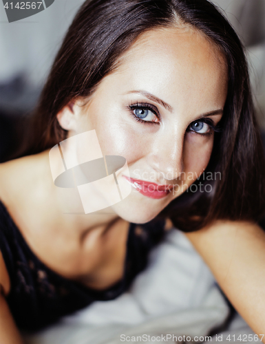 Image of pretty young brunette woman in bedroom interior smiling